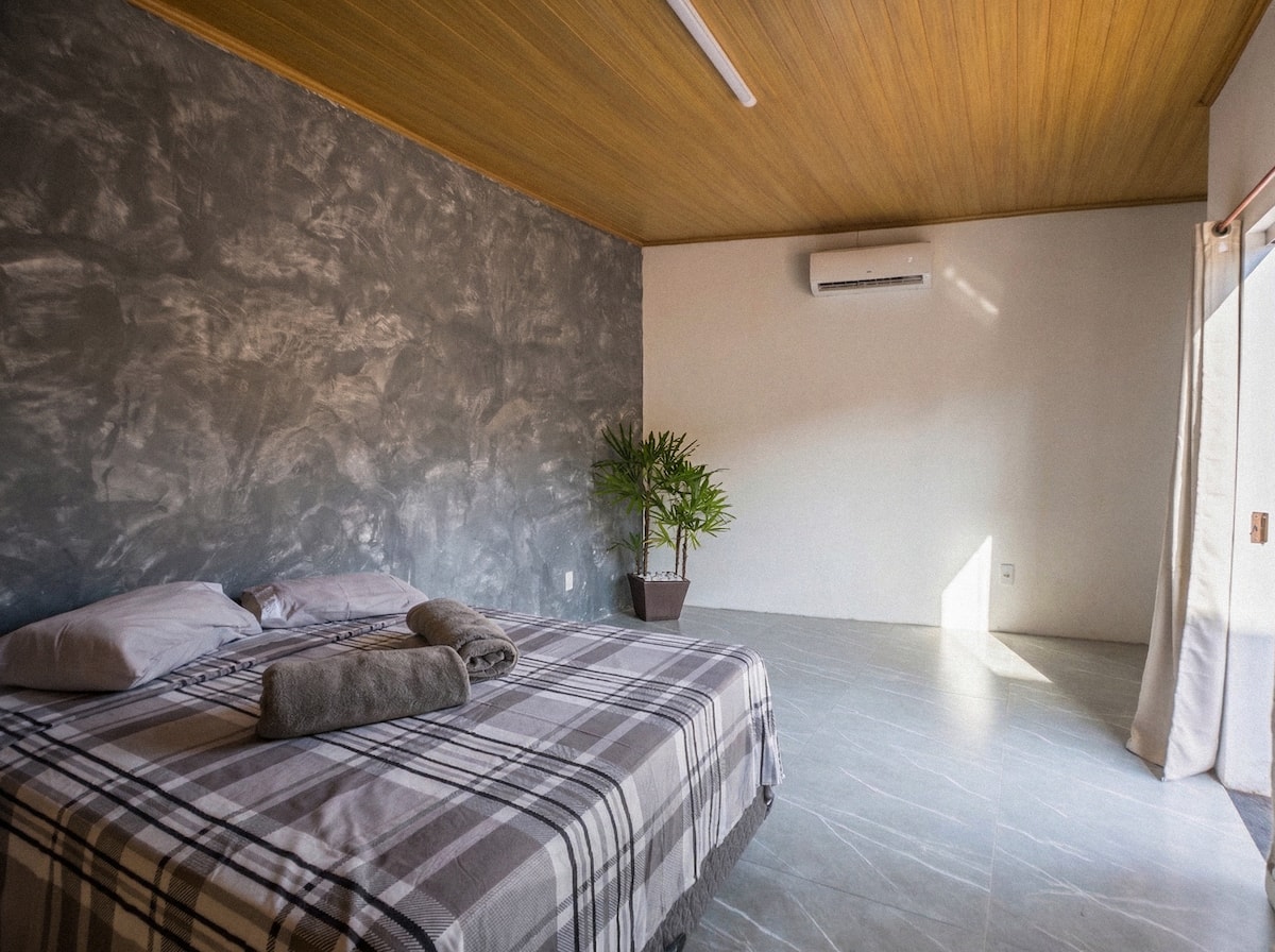 Quarto com cama de casal, parede de pedra e ar-condicionado